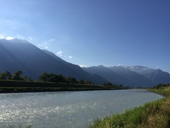 Scenic view of lake and mountains against blue sky