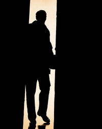 Low section of silhouette man standing against wall