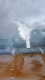 Close-up of waves splashing on beach against sky