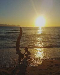 Mother and son playing at beach during sunset