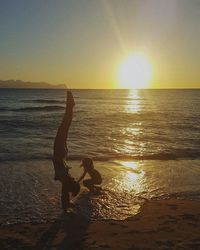 Silhouette people on beach against sunset sky