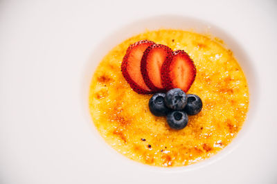 Close-up of orange slice in plate against white background