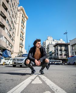 Full length of man sitting against buildings in city