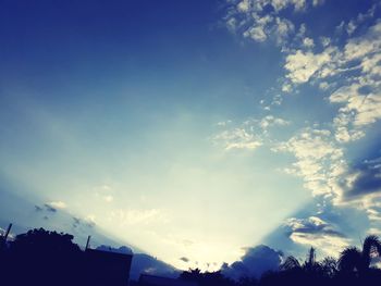 Low angle view of silhouette trees against blue sky