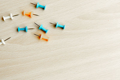 High angle view of colorful thumbtacks on wooden table