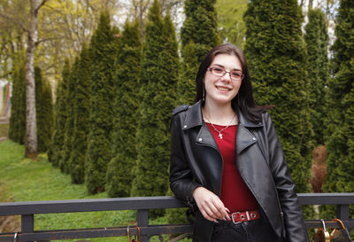 Portrait of smiling young woman standing against trees