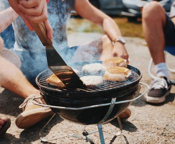 Midsection of man preparing food on barbecue grill