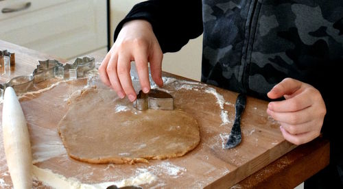 Midsection of person preparing gingerbread for christmas