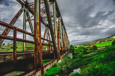 Low angle view of old bridge over field against sky