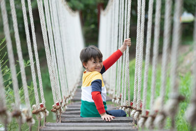 Full length of boy playing with fence