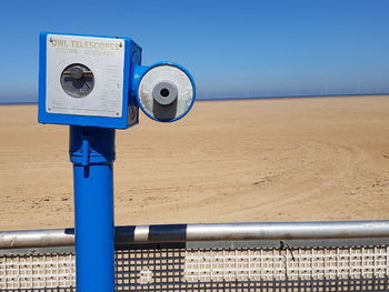 Close-up of coin-operated binoculars against blue sky