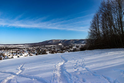 Snow covered landscape against blue sky