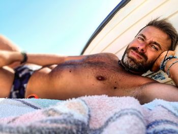 Portrait of shirtless man lying on bed