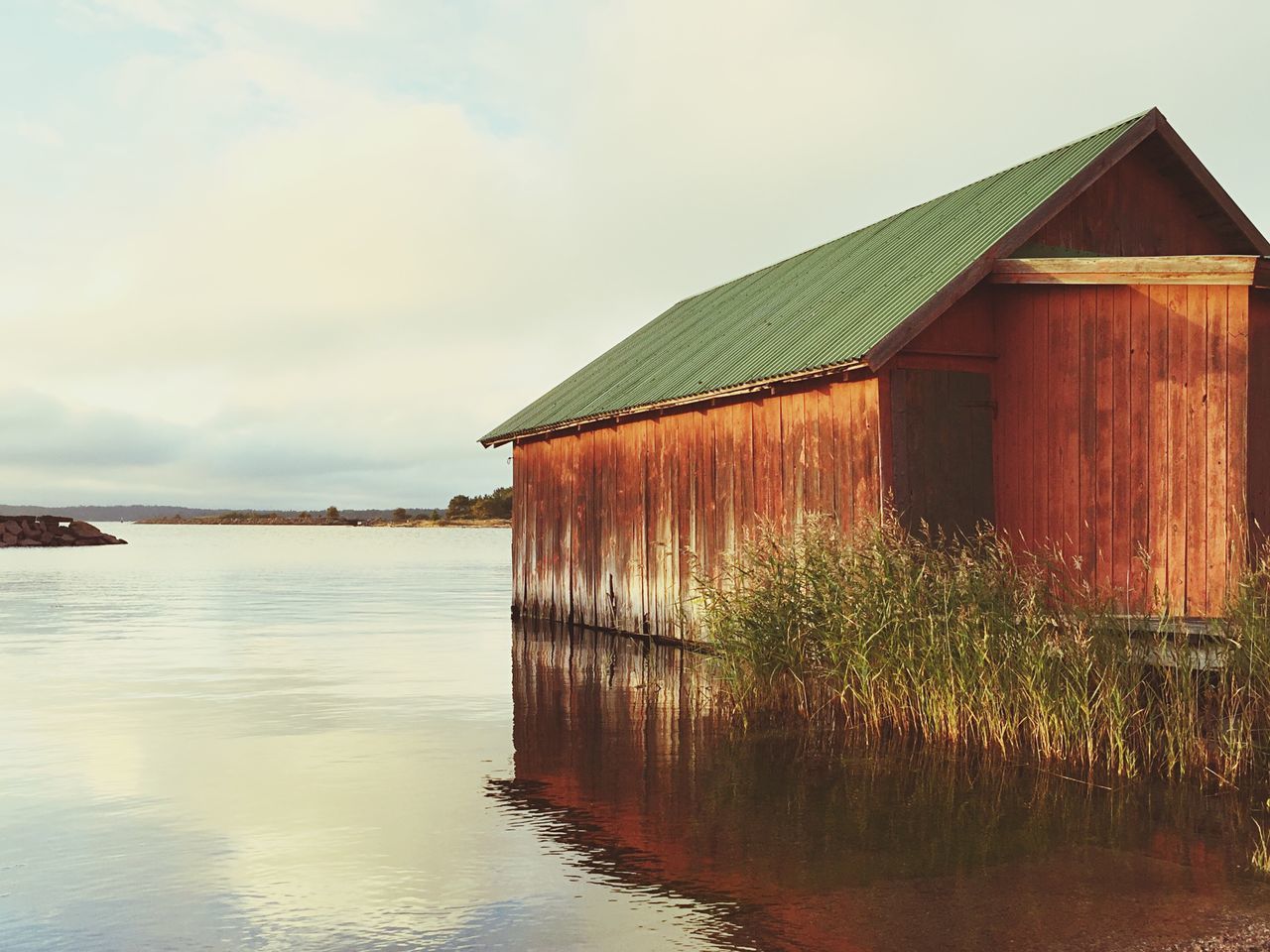 architecture, built structure, building exterior, water, house, sky, cloud - sky, tranquility, cottage, tranquil scene, scenics, cloud, day, nature, beauty in nature, waterfront, in front of, cloudy, outdoors, no people, sea, majestic