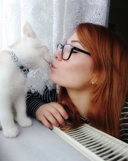 Young woman kissing cat at home