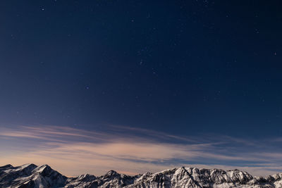 Low angle view of snow covered mountain against blue sky