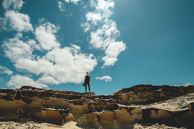 Man standing on rock against sky