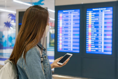 Side view of woman using mobile phone at airport