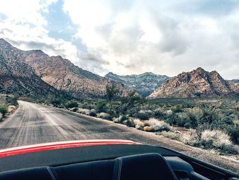 Road by mountains against sky seen through car windshield