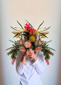 Woman holding bouquet flowers against white background 