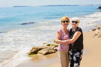 Two senior women are metting on a walk along a rocky beach