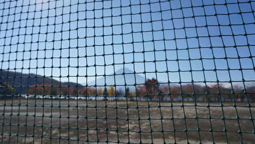 Close-up of chainlink fence in cage against sky