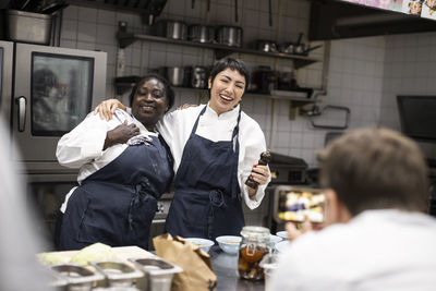 Male chef photographing happy colleagues at commercial kitchen