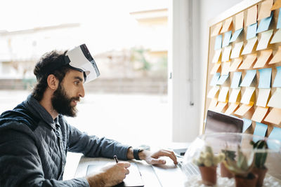 Man with virtual reality glasses working working with graphics tablet and laptop at his office