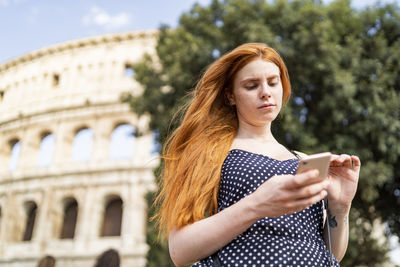 Young tourist browsing smartphone on street