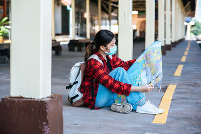 Woman sitting on wall in city