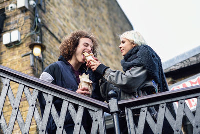 Low angle view of young couple eating in city