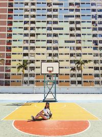 Basketball hoop by swimming pool against buildings