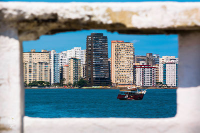 Boats in sea against buildings in city