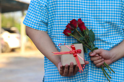 Midsection of person holding red rose in box