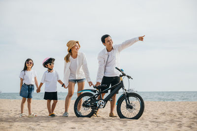 Rear view of man riding bicycle on beach against sky