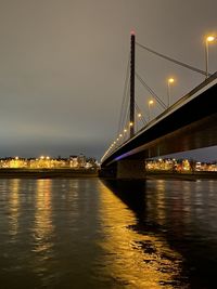 Illuminated bridge over river in city at night