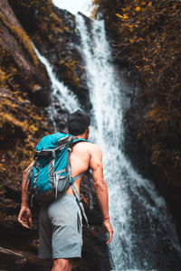 Rear view of man against waterfall