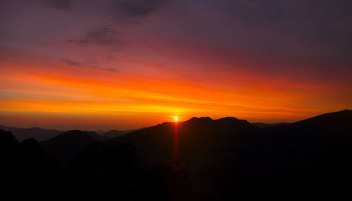 Scenic view of silhouette mountains against romantic sky at sunset