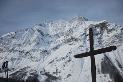 Cross on snowcapped mountain against sky