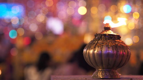 Close-up of antique metal container against illuminated lights at night