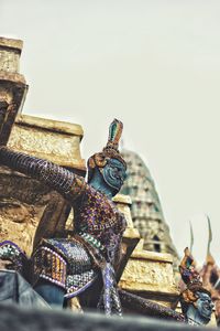 Low angle view of buddha statue against sky