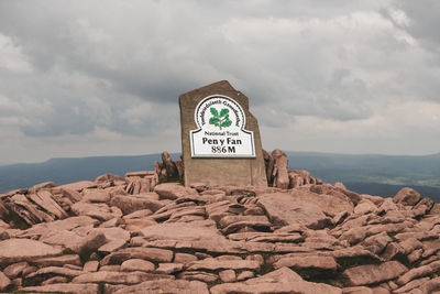 Information sign on rock by sea against sky