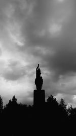 Low angle view of silhouette statue against cloudy sky