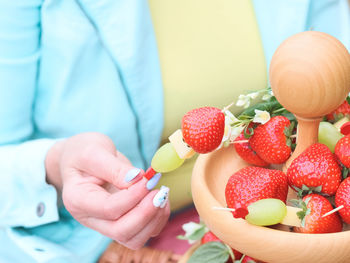 Hands of a caucasian young unrecognizable woman holding a fruit barbecue.