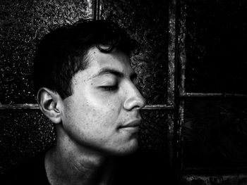 Close-up portrait of young man looking away against wall