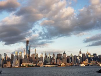 Sea by modern buildings against sky in city