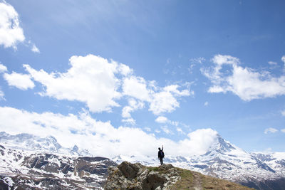 Rear view of young hiker standing in front of snowcapped mountains