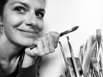 Portrait of smiling woman holding paintbrush at home