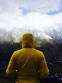 Rear view of man standing against mountain during winter