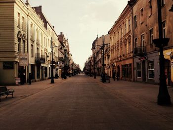 Empty road amidst buildings in city